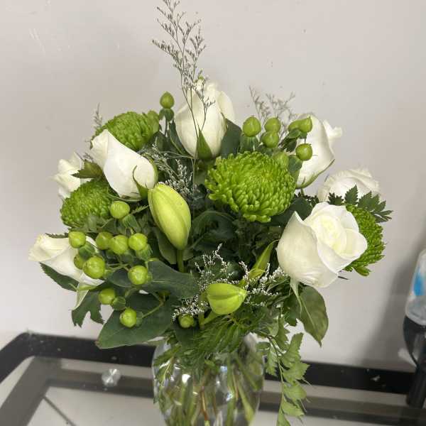 White roses and green chrysanthemums in a glass vase