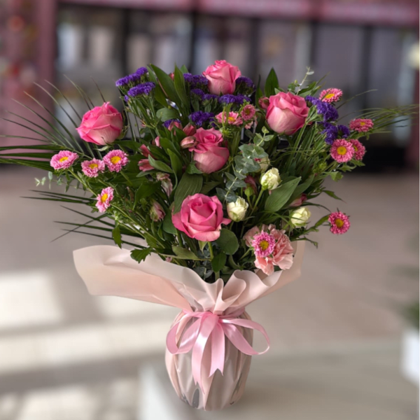 Pink roses and small mixed flowers in a wrapped vase arrangement