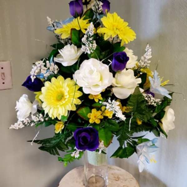 Mixed bouquet of yellow, white, and purple flowers in a clear glass vase