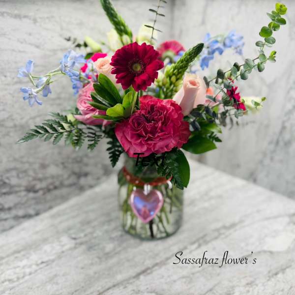 Mixed bouquet in a glass jar with pink, red, and blue flowers