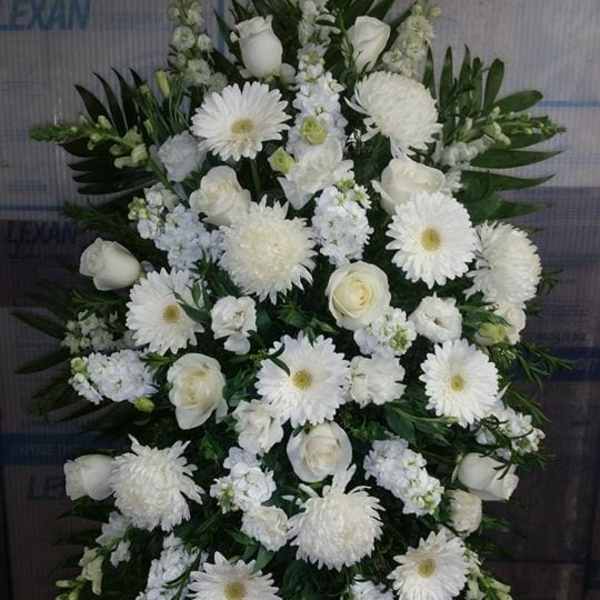 White funeral spray with roses and daisies on a stand