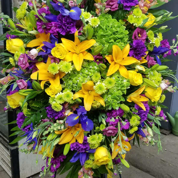 Large standing spray with yellow lilies, purple flowers, and green hydrangeas