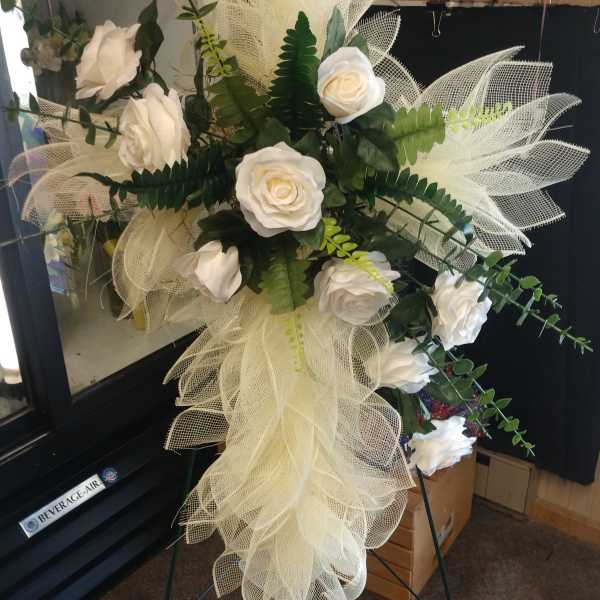 White rose funeral spray with mesh ribbon on a standing easel