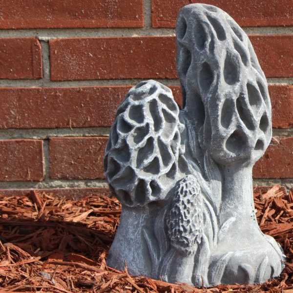 Gray mushroom-shaped garden sculpture beside a brick wall