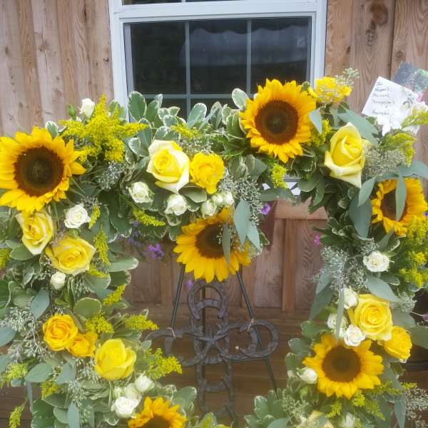 Sunflower and yellow rose wreath on a metal stand