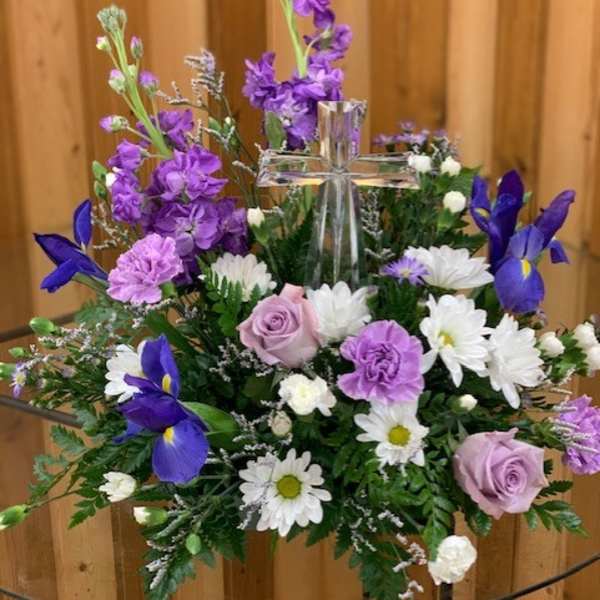 Purple and white floral arrangement with a clear glass cross centerpiece