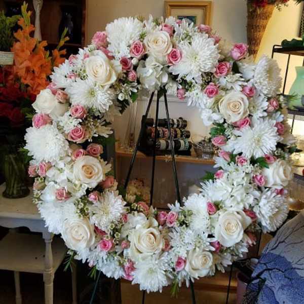 Large floral wreath with white and pink roses and white mums on an easel
