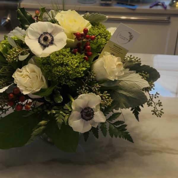 White roses and anemones arranged with green filler in a low bouquet.