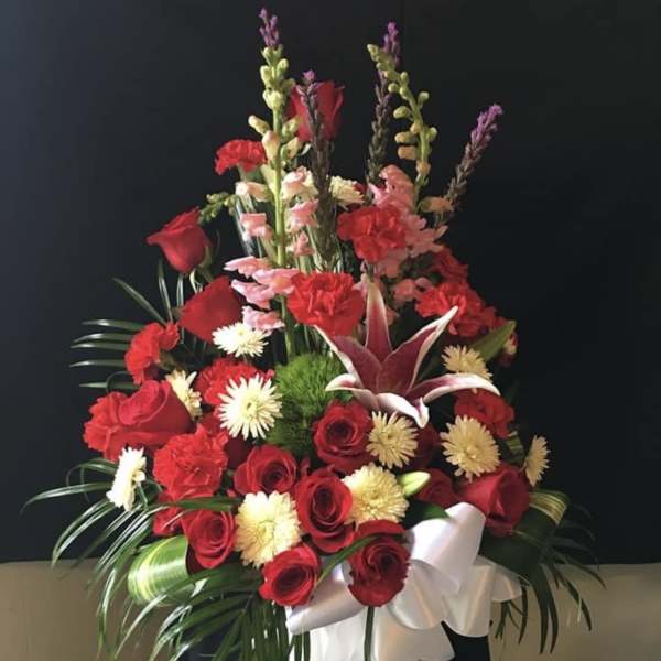Red and white floral arrangement in a white vase with a ribbon