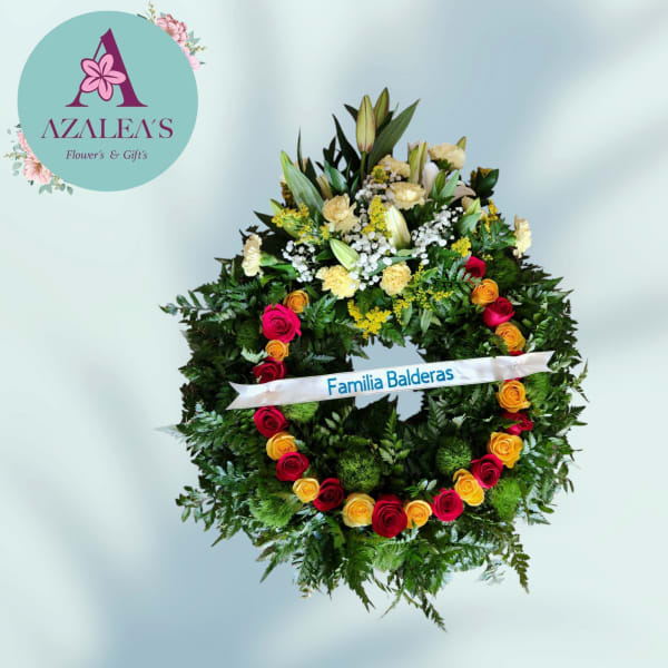 Large floral wreath with red, yellow, and pink roses and a white ribbon