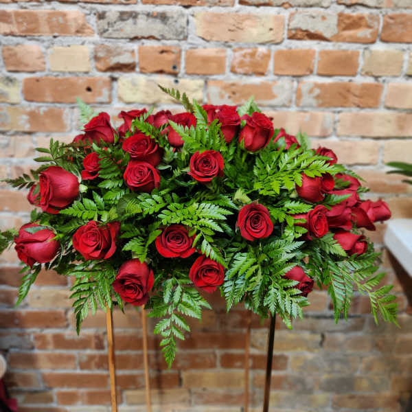 Red roses arranged in a low spray with fern foliage