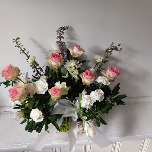 Pink and white rose arrangement with white ribbon in a basket