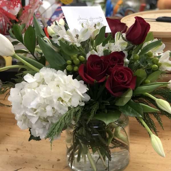 Bouquet of red roses, white hydrangea, and white tulips in a glass vase
