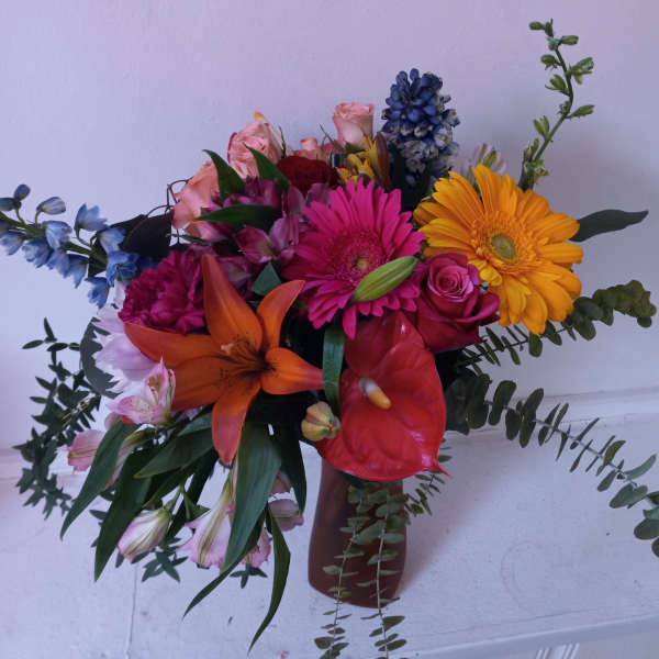 Colorful mixed bouquet in a vase with gerbera daisies, roses, lilies, and anthurium
