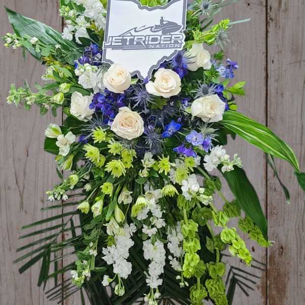 Standing floral spray with white roses, blue flowers, and green accents