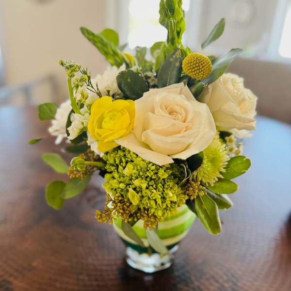 Small bouquet of cream and yellow roses in a glass vase