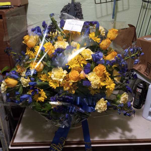 Large bouquet of yellow and blue flowers wrapped in clear plastic