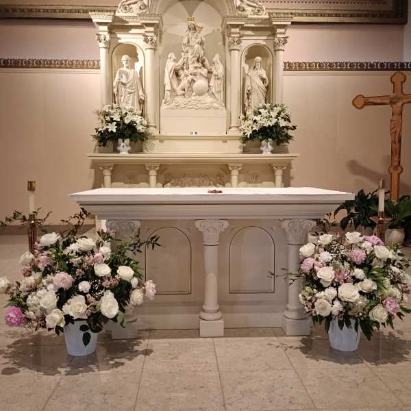 White and pink floral arrangements around a church altar and casket