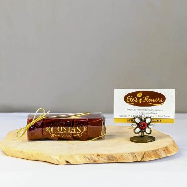 Wood slab display with wrapped chocolates and a florist business card in a small flower-shaped holder.