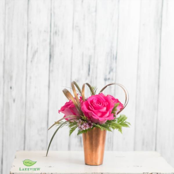 Pink roses in a copper vase with greenery