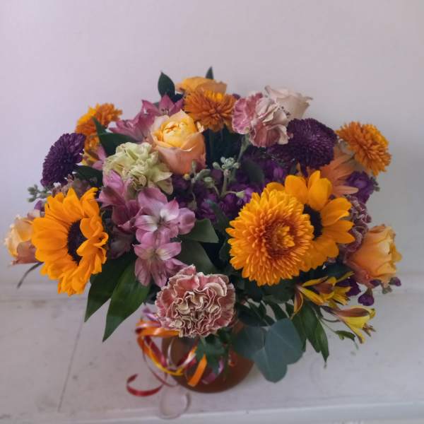 Mixed bouquet with orange sunflowers and purple blooms in a vase