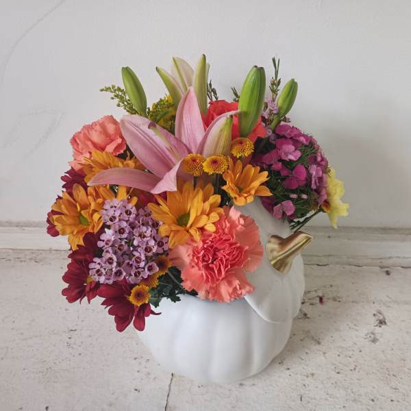 Colorful flower arrangement in a white pumpkin-shaped vase