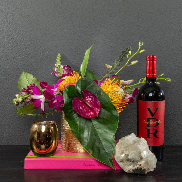 Tropical floral arrangement with a wine bottle and gold candle holder