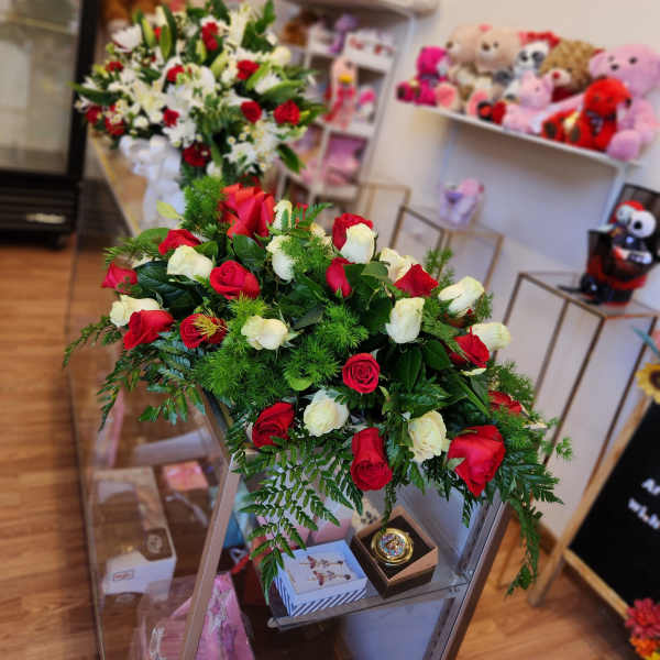 Two rose arrangements in a shop, one red and white bouquet in front and one mixed bouquet behind.