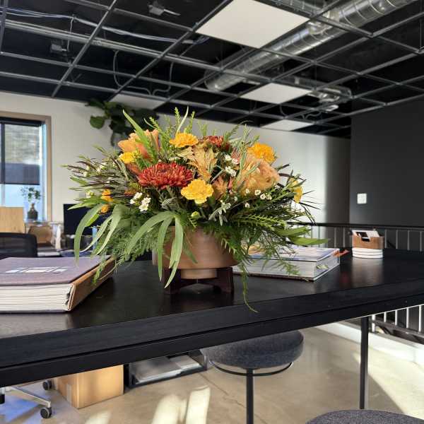Low floral centerpiece with orange and yellow blooms in a round vase