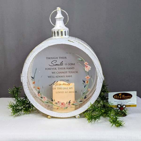 White memorial lantern with floral accents and a sympathy message