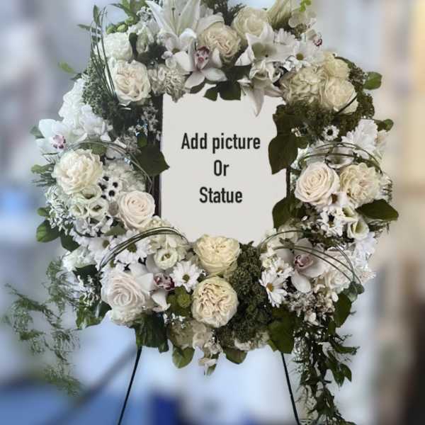 White floral wreath on an easel with a center space for a photo or statue