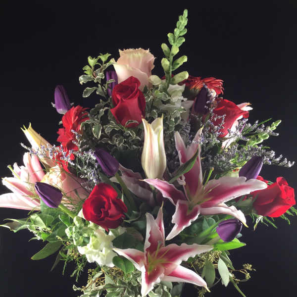 Mixed bouquet of red roses and pink lilies in a glass vase