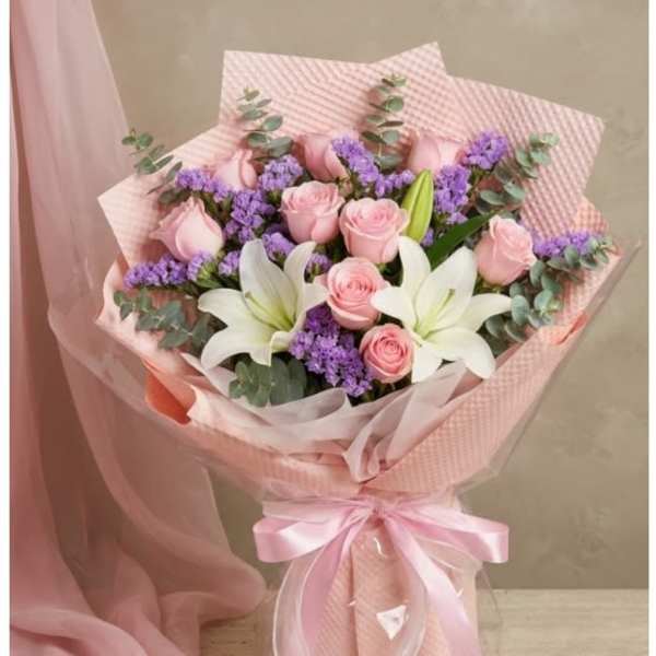 Pink roses and white lilies in a wrapped bouquet with a satin ribbon