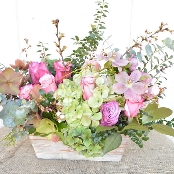 Pink roses and green hydrangeas in a white wooden box with eucalyptus