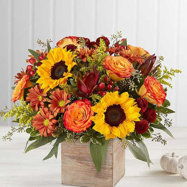 Autumn bouquet with sunflowers, orange roses, and red mums in a wooden box