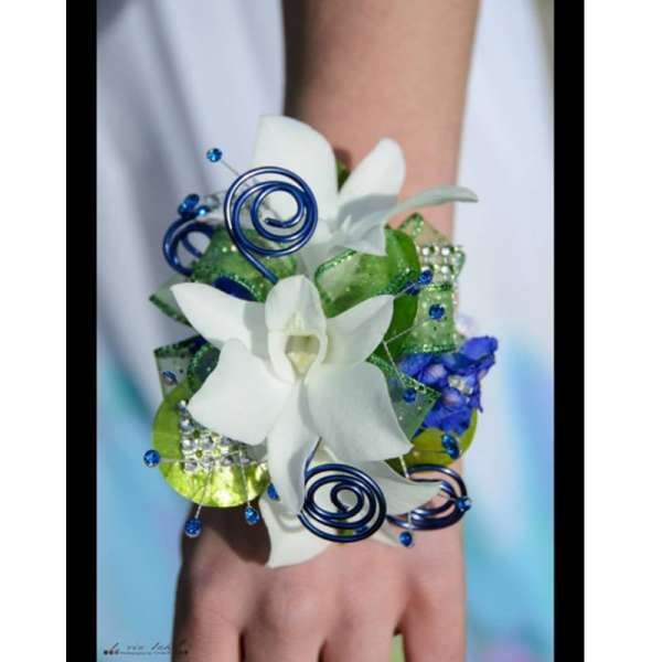 White orchid wrist corsage with blue spiral accents and green ribbon