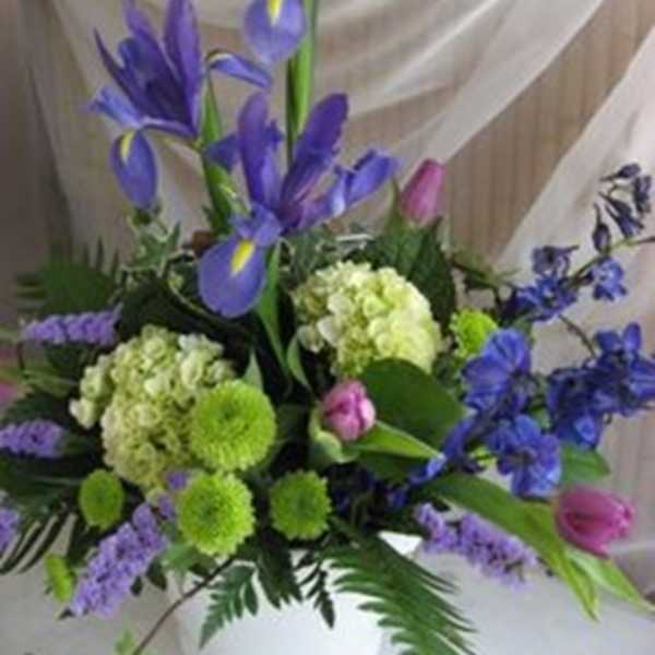 Purple iris and green pompom flowers in a white vase