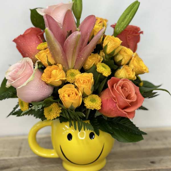 Bouquet of roses and lilies in a yellow smiley-face mug
