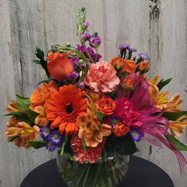Bright mixed bouquet in a glass vase with orange, pink, and purple flowers
