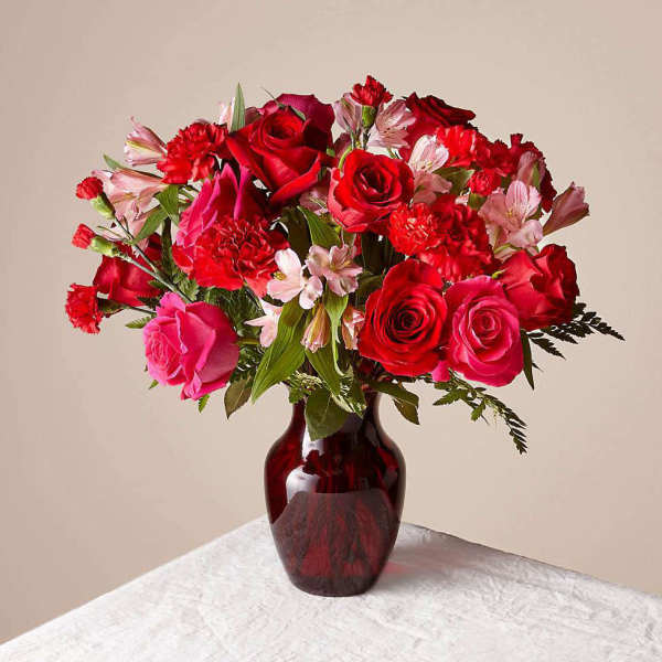 Red and pink rose bouquet in a dark glass vase