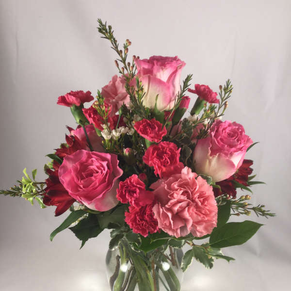 Pink roses and carnations in a clear glass vase