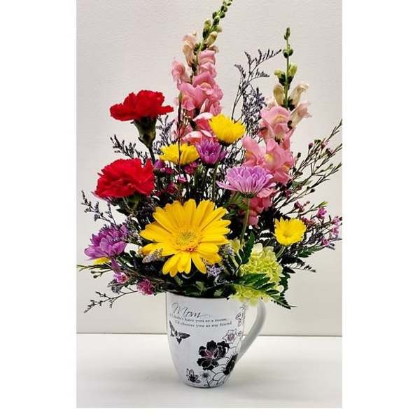 Colorful mixed flowers arranged in a white mug vase