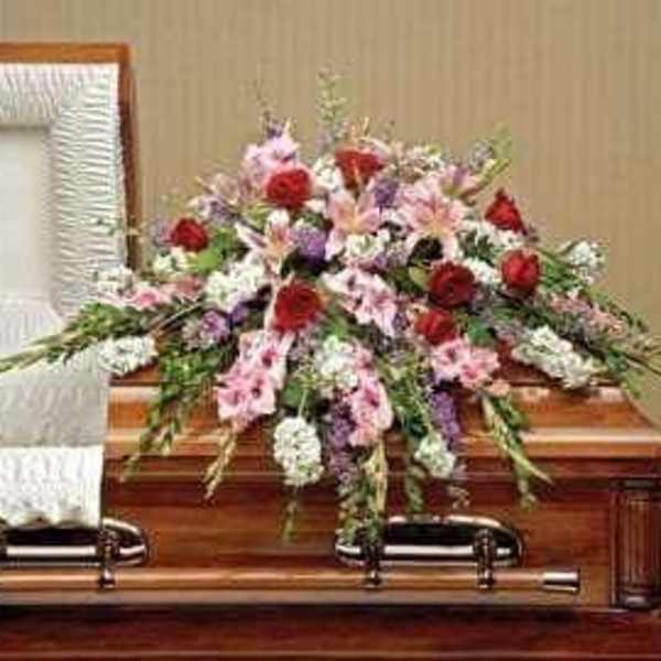 Floral spray on a wooden casket with pink, red, and white flowers
