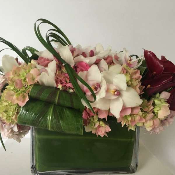 Pink and white floral arrangement in a square glass vase