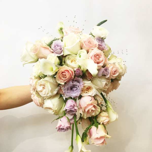 Handheld bouquet of pastel roses and calla lilies