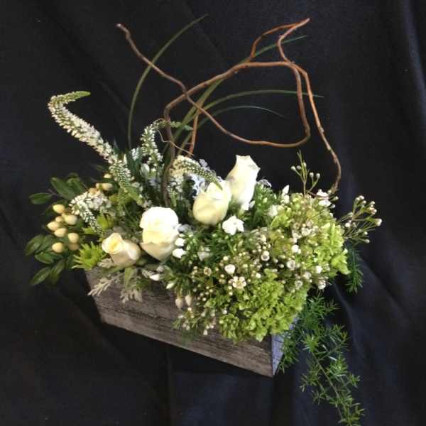 White flowers and green blooms arranged in a rustic wooden box