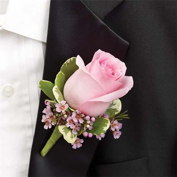 Pink rose boutonniere with small purple flowers on a black suit lapel