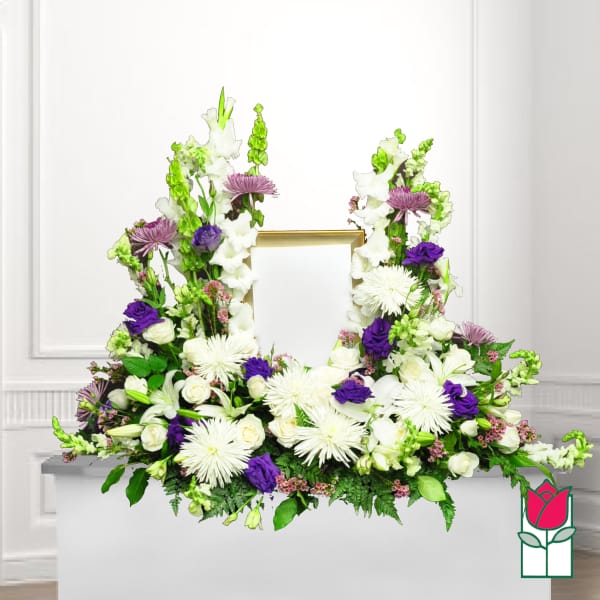 White and purple floral funeral frame arrangement with a gold photo opening