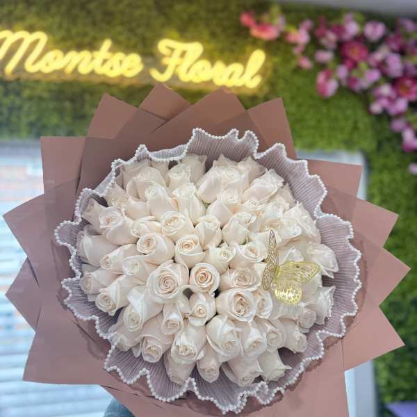 Bouquet of pale cream roses wrapped in pink paper