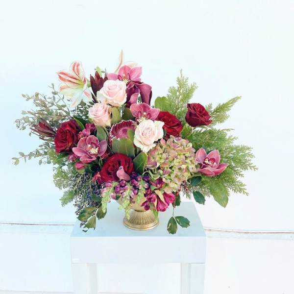 Mixed bouquet of pink and red flowers in a gold vase